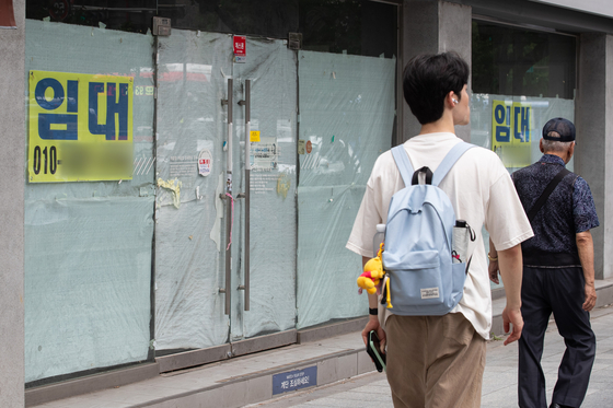 Pedestrians pass by a vacant office for rent. [NEWS1]