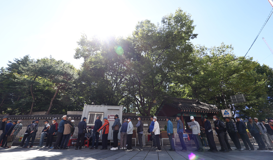 Elderly people stand in line at a soup kitchen set up outside Tapgol Park in Jongno District, central Seoul, on Wednesday, which also marks Senior Citizens' Day in Korea. Approximately 40 percent of the 10 million people aged 66 and over live in poverty, according to an OECD report published in December. Government statistics released earlier in the year show about a quarter of people aged 70 and above still work. [YONHAP]