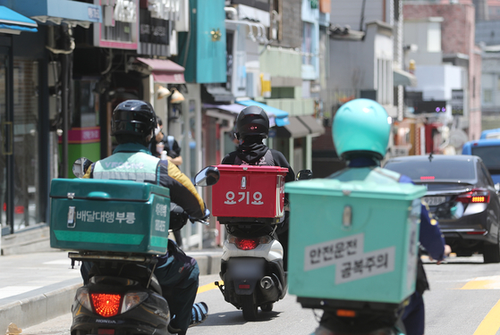 Delivery drivers ride on a street in Seoul on May 24, 2021. [NEWS1]