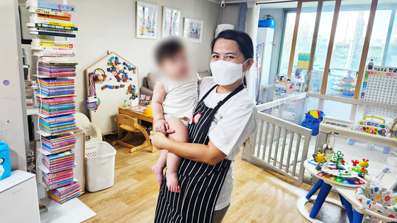 A Filipino caregiver holds a baby at a home in Seoul. [SEOUL METROPOLITAN GOVERNMENT]