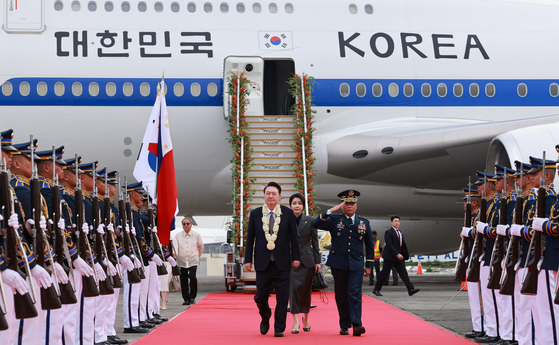 President Yoon Suk Yeol, left, and first lady Kim Keon Hee, center, are received by an honor guard as they arrive at Ninoy Aquino International Airport in Manila for a state visit to the Philippines on Sunday. Yoon began a six-day visit to the Philippines, Singapore and Laos to take part in bilateral summits and attend a series of Asean-related meetings. [JOINT PRESS CORPS]