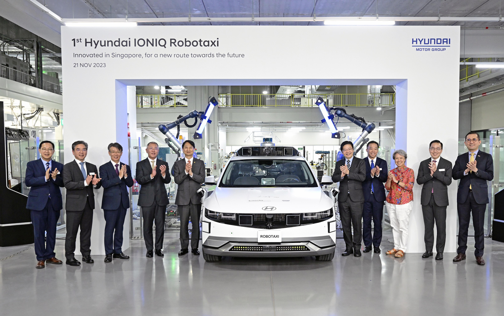 Hyundai Motor Group Executive Chair Euisun Chung, fourth from left, and other executives and government officials take a photo with the Ioniq 5 Robotaxi celebrating the opening of the Global Innovation Center Singapore in Singapore in November last year. [HYUNDAI MOTOR]