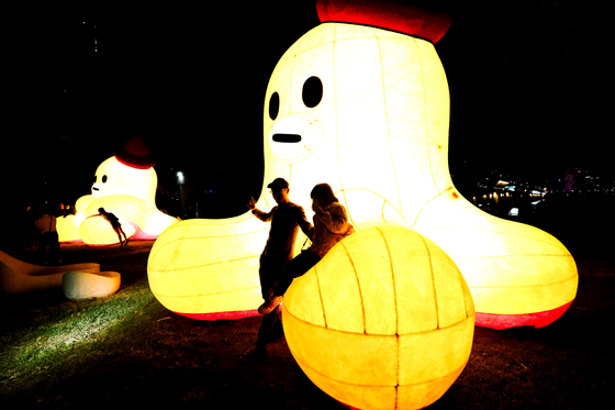 Attendees take photos with the LG U+ character Moono during the 2024 Seoul Light Hangang Bitseom Festival at Yeouido Hangang Park in western Seoul. [LG U+]