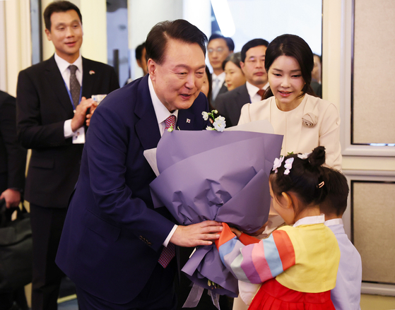 President Yoon Suk Yeol, left, accompanied by first lady Kim Keon Hee, receives flowers from children at a luncheon for Korean compatriots at a hotel in Singapore on Wednesday. [JOINT PRESS CORPS]