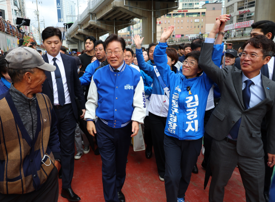 Democratic Party leader Lee Jae-myung, third from left, walks alongside Kim Kyung-ja, second from right, who is the party's candidate for chief of Busan's Geumjeong District, near Oncheoncheon, a stream that runs through the area.