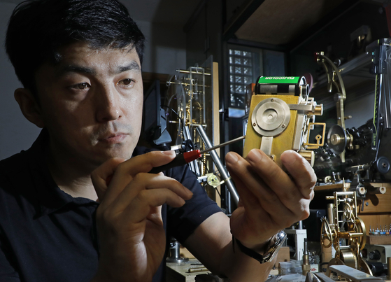 Metal artist Hyun Kwang-hun focuses on assembling watch parts at his studio located in Huam-dong, Yongsan District, central Seoul.  [PARK SANG-MOON] 