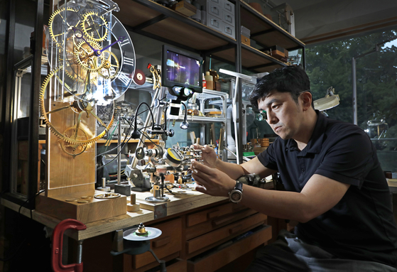 Metal artist Hyun Kwang-hun focuses on assembling watch parts at his studio located in Huam-dong, Yongsan District, central Seoul.  [PARK SANG-MOON] 