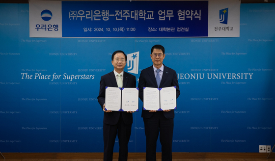 President of Jeonju University Park Jin-bae, left, and Kim Beom-seok, head of Woori Bank's Domestic Business Division, sign a memorandum of understanding at Jeonju University's campus in Jeonju, North Jeolla, on Thursday. [JEONJU UNIVERSITY]