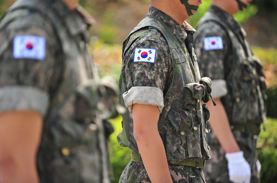 Three men are seen wearing military uniform with the Korean national flag attached. [SHUTTERSTOCK]