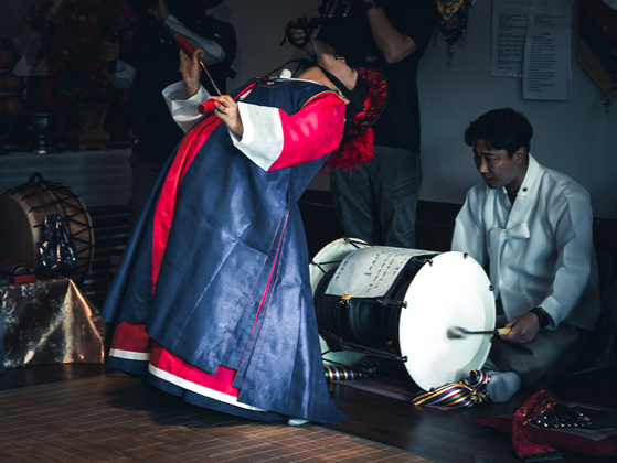 A shaman, accompanied by a musician, performs a gut (Korean shamanistic ritual) at a gutdang (ritual hall) in Gyeonggi in May 2023. Photo taken for Tving documentary "Shaman: Whispers from the Dead." [CHO WON-SIK]