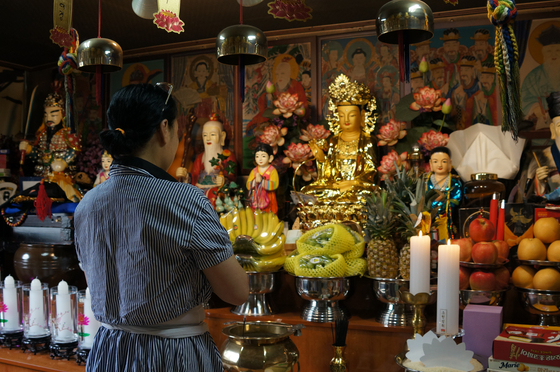 Shaman Kim Jung-hee prays at her shindang, or shrine, inside her home in Seoul. Kim is the author of book "God's will, god's way" (translated) published in 2021. [KIM JU-YEON]