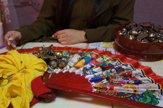 Shaman Kwon Soo-jin asks her clients for their name and birthdate and examines their hands when fortune-telling. She will sometimes use bells, or a fan, to call upon deities. [KIM JU-YEON]