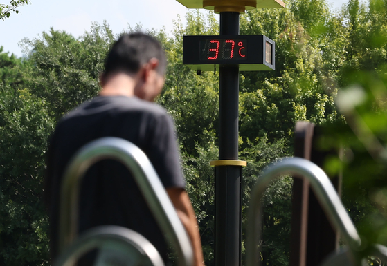 A person swelters in front of a thermometer indicating daily temperature of 37 degrees Celsius (98.6 degrees Fahrenheit) in Seocho District, southern Seoul, on Aug. 19. [YONHAP] 