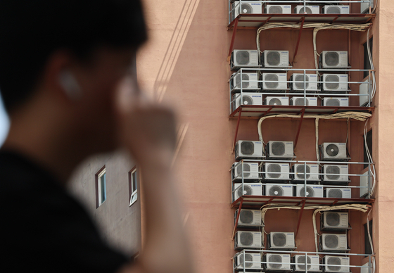 Condenser units connected to indoor air conditioners operate outside of a building in downtown Seoul on Aug. 14. [NEWS1]