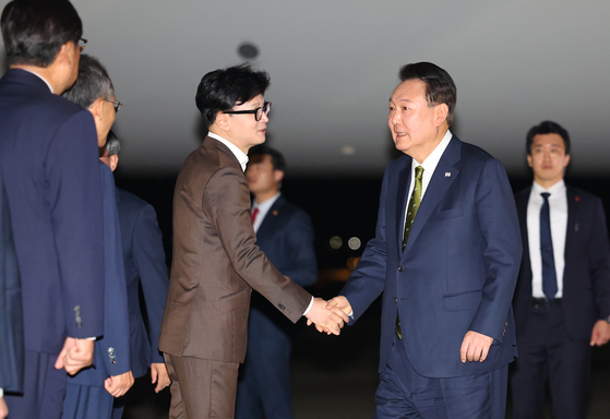 President Yoon Suk Yeol, right, shakes hands with People Power Party chief Han Dong-hoon at Seoul Air Base in Seongnam, Gyeonggi, on Saturday after returning from a six-day, three-country trip to Southeast Asia for bilateral summits and Asean-related meetings. [JOINT PRESS CORPS]