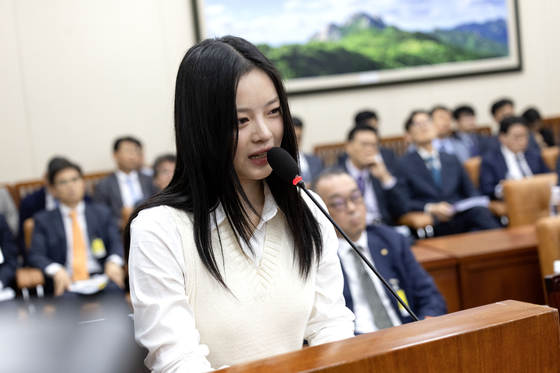 Hanni of girl group NewJeans sheds tears while testifying at the National Assembly's Environment and Labor Committee on Oct. 15 in western Seoul. [JOINT PRESS CORPS]