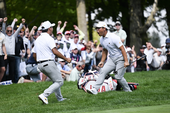 Tom Kim, right, of the International Team celebrates with teammate Kim Si-woo after a birdie on the 14th hole during four-Ball matches on day three of the 2024 Presidents Cup at The Royal Montreal Golf Club on Sept. 28 in Montreal, Quebec. [GETTY IMAGES]