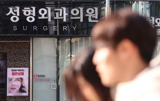 People walk by a plastic surgery clinic in downtown Seoul on Jan. 28. [YONHAP] 