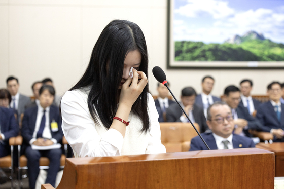 Hanni of girl group NewJeans sheds tears while testifying at the National Assembly's Environment and Labor Committee on Oct. 15 in western Seoul. [JOINT PRESS CORPS]