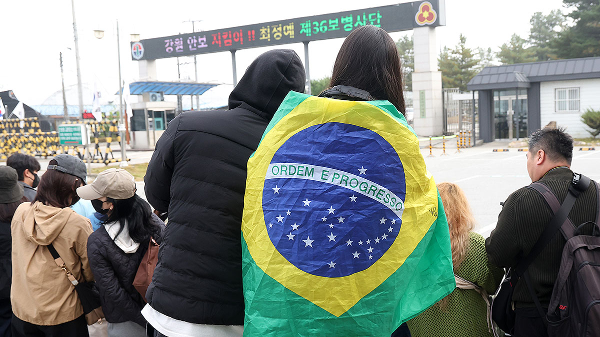 Fans await BTS member J-Hope in front of his base camp in Wonju, Gangwon, on Oct. 17. One fan is seen wearing the Brazilian flag around her shoulders. [YONHAP]