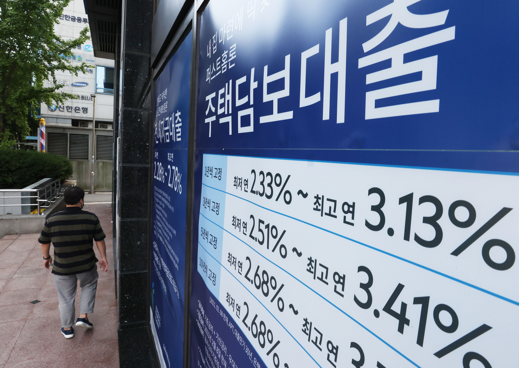 A person walks by a sign about a bank's loan programs that was put up by a lender in Seoul. [YONHAP] 