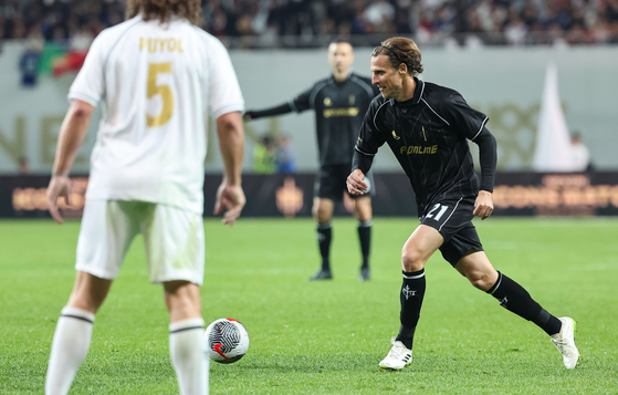 Diego Forlan dribbes past Carles Puyol  [NEWS1]