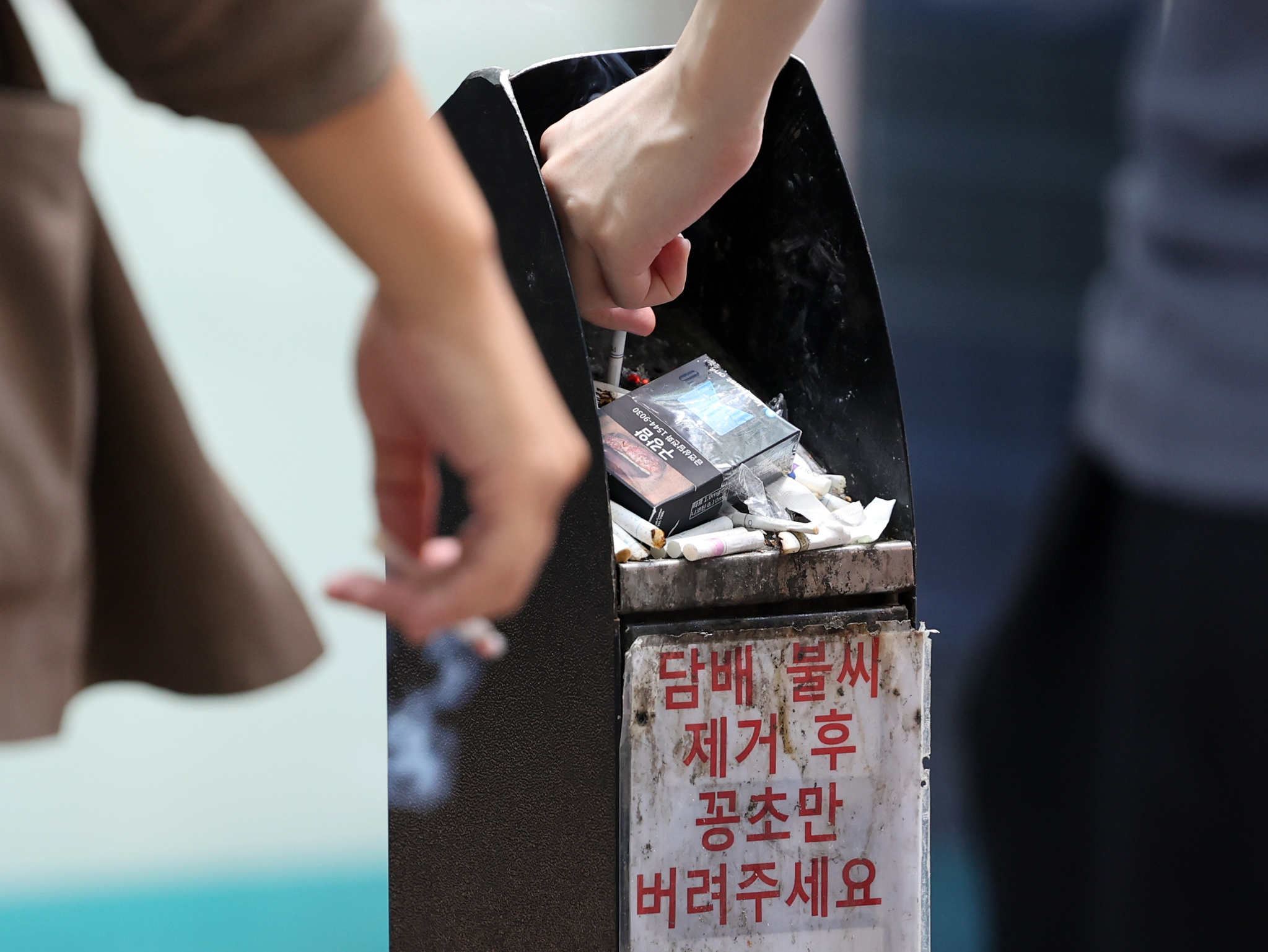 Smokers dispose of their cigarette butts at a smoking zone in Jongno District, central Seoul, on Aug. 14. [NEWS1] 