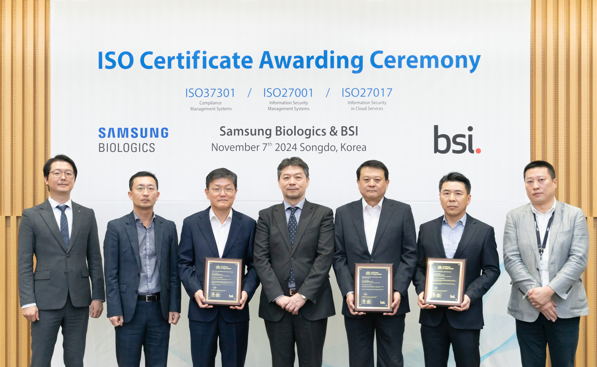 Third from left, Samsung Biologics Executive VIce President Kim Dong-joong, BSI Korea CEO Lim Seong-hwan and Samsung Biologics Executive Vice President Lee Kyu-ho pose for a photo with ISO certifications at the firm's headquarters in Incheon on Thursday. [SAMSUNG BIOLOGICS]