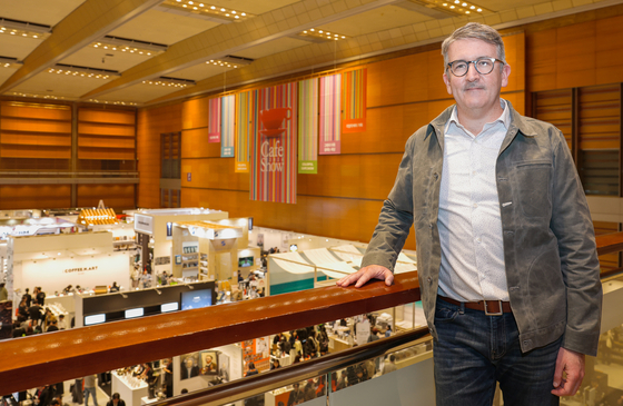 Intelligentsia Coffee CEO James McLaughlin poses for a photo ahead of an interview with the Korea JoongAng Daily at Coex in southern Seoul on Nov. 6. It was also the first day of the combined Seoul Cafe Show and the ninth Seoul Coffee Festival, for which booths are pictured in the exhibition space. [SEOUL CAFE SHOW]